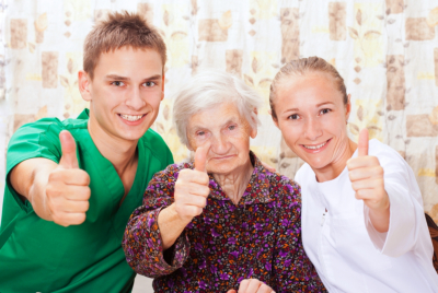 caregivers and senior woman posing thumbs up